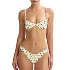 Woman wearing a polka dot bikini set on a plain background