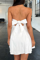 White dress with a bow detail on the back worn by a person indoors.