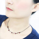 Stylish woman's neck showcasing an AAA grade CZ necklace with red gemstones on a delicate chain