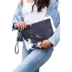 Stylish animal print clutch bag held by a model wearing a denim jacket and casual jeans