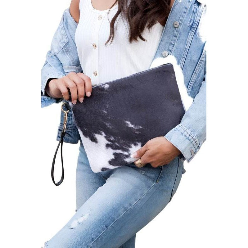 Stylish animal print clutch bag held by a model wearing a denim jacket and casual jeans