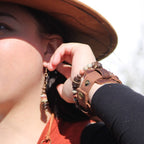 A woman wearing aqua terra and wood earrings paired with a stylish leather bracelet outdoors