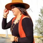 Woman wearing aqua terra and wood earrings with a stylish hat and layered jewelry for a fashionable look