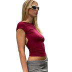 Woman wearing a backless clubwear slim fit top in maroon paired with gray pants and white sunglasses