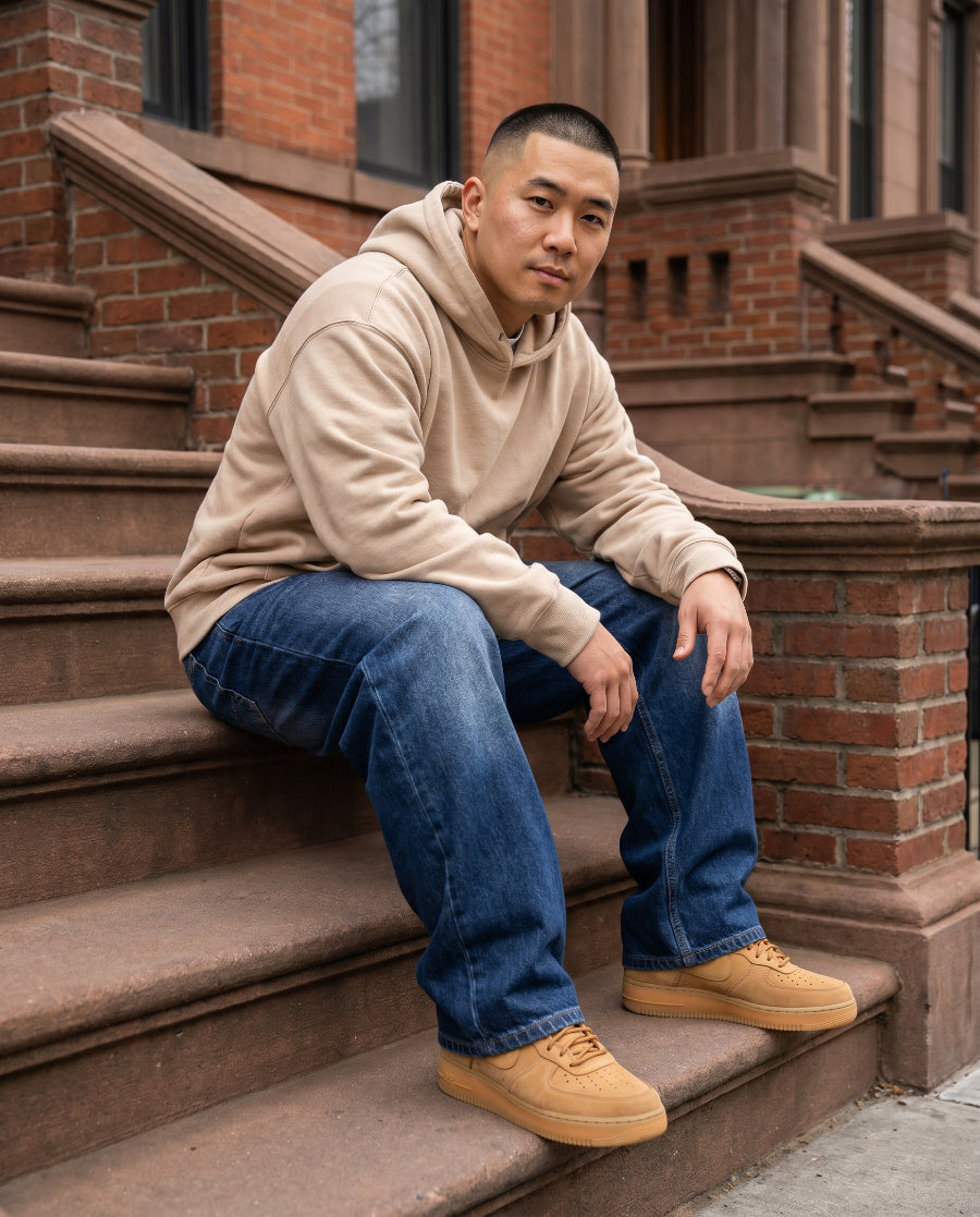 Man wearing dark blue wide-leg baggy jeans seated on Brooklyn brownstone stoop, relaxed street style