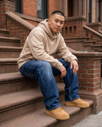 Man wearing dark blue wide-leg baggy jeans seated on Brooklyn brownstone stoop, relaxed street style
