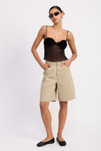 Model wearing sheer mesh floral cami top in black with ruched floral cups paired with beige bermuda shorts and black flats