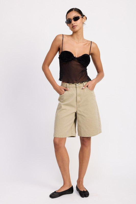 Model wearing sheer mesh floral cami top in black with ruched floral cups paired with beige bermuda shorts and black flats