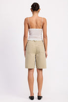 Back view of model wearing Emory Park sheer mesh floral cami top with thin straps scalloped hem and beige knee length shorts