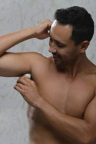Man applying BeNat all natural deodorant for travel essentials on his underarm