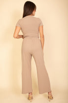Back view of woman wearing beige wide-leg pants and short-sleeve top outfit by VacationGrabs for black casual travel outfit