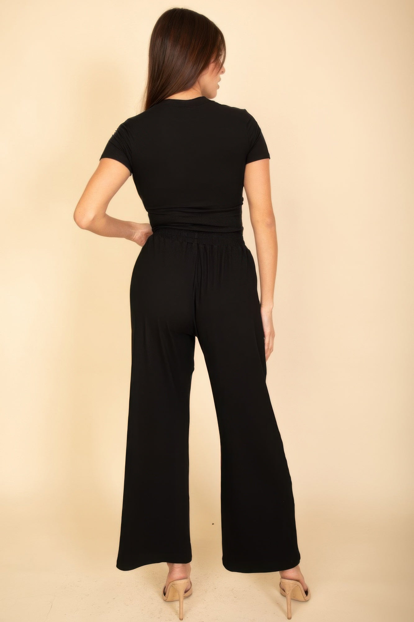 Woman wearing a black casual travel outfit from VacationGrabs with short sleeves and wide-leg pants