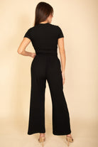 Woman wearing a black casual travel outfit from VacationGrabs with short sleeves and wide-leg pants