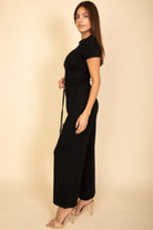 Woman wearing a black casual travel outfit with short sleeves and wide-leg pants by VacationGrabs