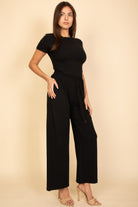 Woman wearing a black casual travel outfit with a fitted top and wide-leg pants by VacationGrabs