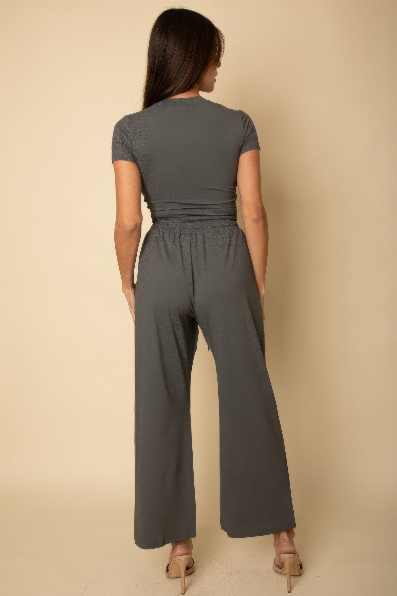 Back view of woman wearing a black casual travel outfit with short sleeves and wide-leg pants