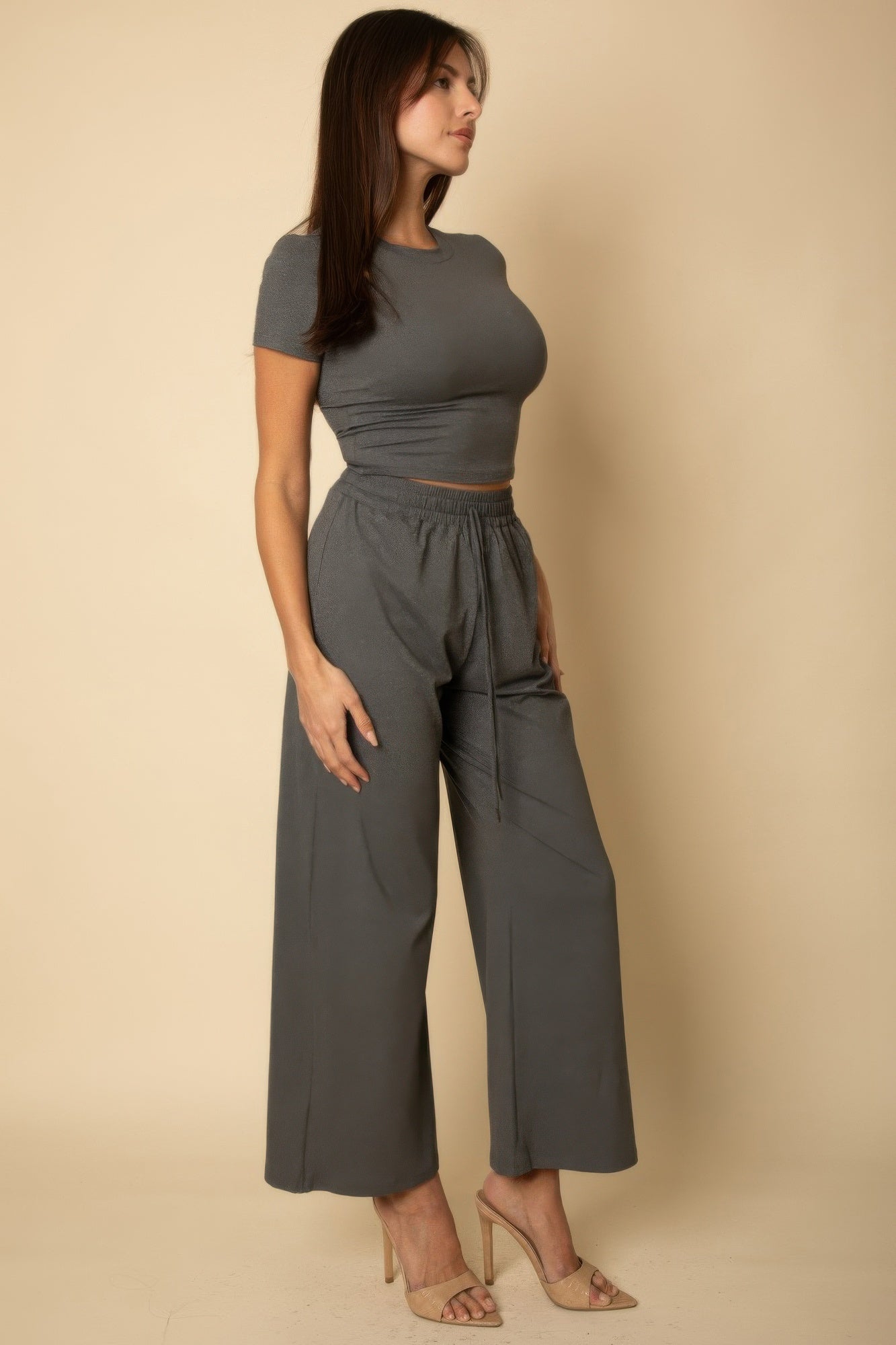 Woman wearing a black casual travel outfit consisting of a fitted crop top and wide-leg pants