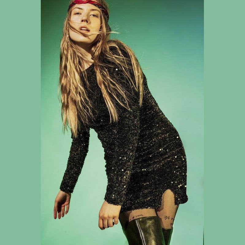 Stylish woman wearing a black embellished mini dress with a fitted silhouette and long sleeves