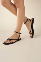 Women wearing black flat strappy sandals from Top Guy Footwear with a stylish and comfortable design