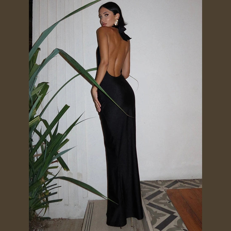 Elegant black halter deep v neck maxi dress with open back worn by woman posing indoors