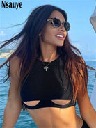 Woman wearing black hollow out crop top with sleeveless design and cutout details by the water