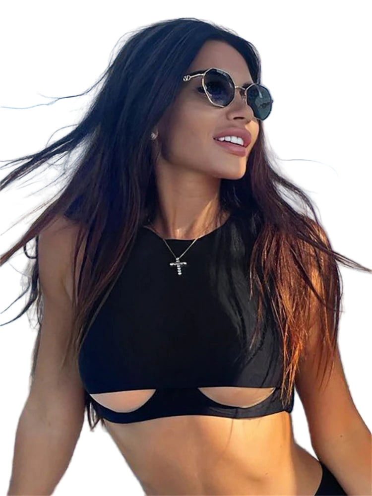 Woman wearing black hollow out crop top with sleeveless design and cutout details by the water