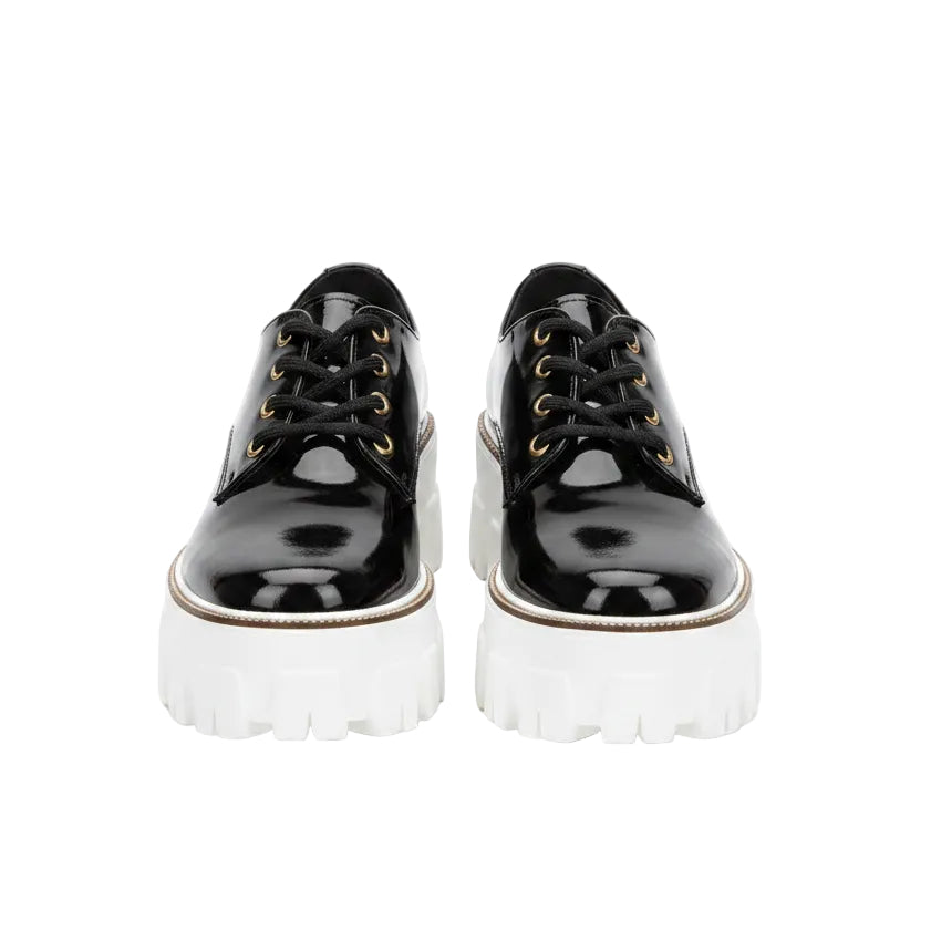 Black platform shoes worn with blue jeans on a white background