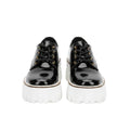 Black platform shoes worn with blue jeans on a white background