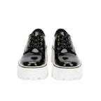 Black platform shoes worn with blue jeans on a white background