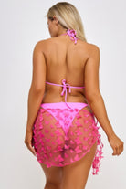 Back view of a woman in a pink blossom bikini set with a sheer butterfly cover-up for stylish beach outings