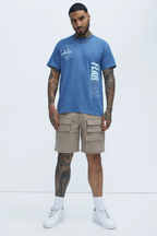 Men's blue fearless graphic tee by VacationGrabs paired with beige cargo shorts and white sneakers