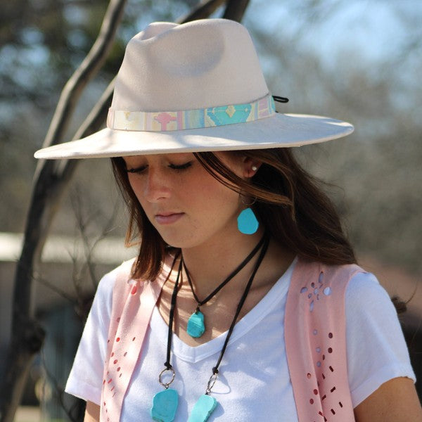 Model wearing blue turquoise chunky earrings with a wide-brimmed hat and stylish outfit