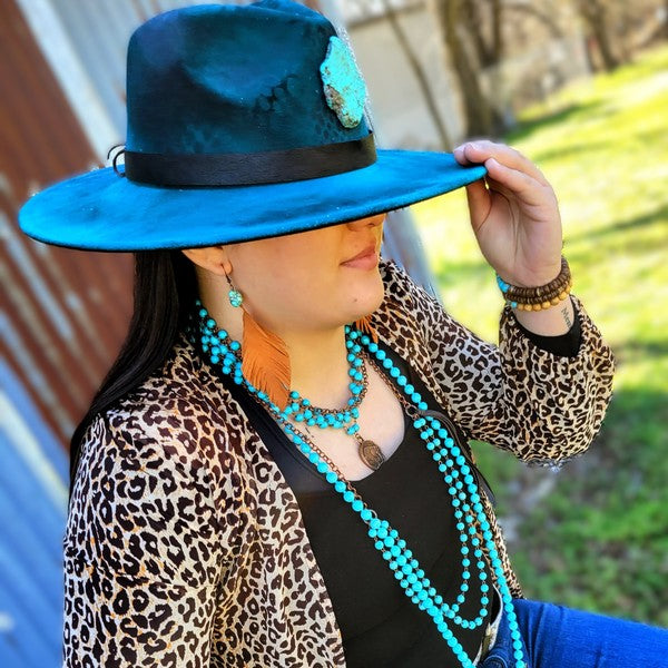 Model wearing a blue turquoise coin necklace with matching earrings and stylish hat outdoors