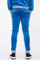 Back view of blue velour jogger pants with white patterned trim and buttoned back pockets