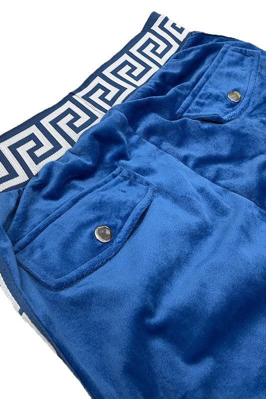 Close-up of blue velour jogger pants with snap button pockets and decorative patterned waistband