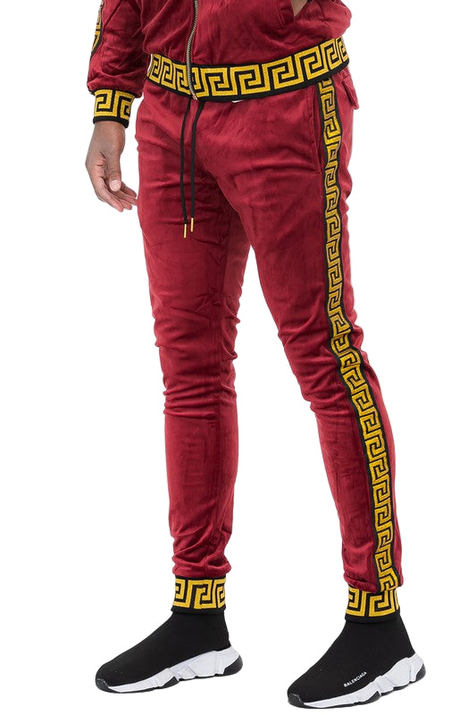 Red velour jogger pants with yellow Greek key pattern trim from WEIV, styled with black slip-on sneakers