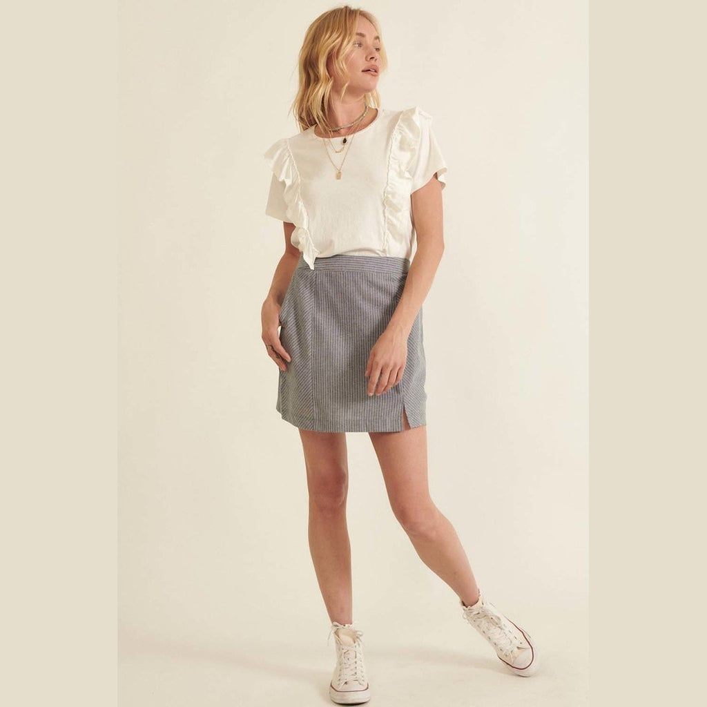 Woman wearing a chic pinstripe skirt for women paired with white ruffle sleeve top and sneakers