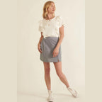 Woman wearing a chic pinstripe skirt for women paired with white ruffle sleeve top and sneakers
