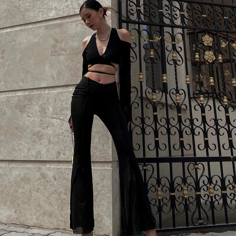 Woman wearing sheer streetwear crop tee for women paired with black flared pants standing by decorative iron gate
