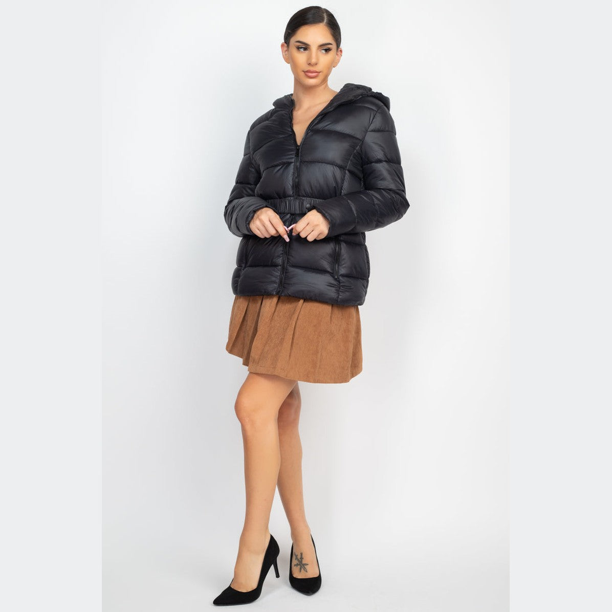 Woman wearing a casual A-line corduroy skirt and black puffer jacket with black heels