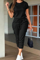 Women's casual crew neck short sleeve jumpsuit in black with stylish jogger pants and adjustable waist.