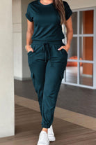 Women in a green casual crew neck short sleeve jumpsuit with pockets and adjustable drawstring waist