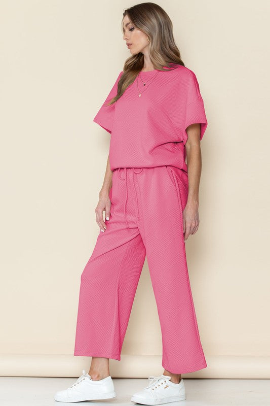 Woman wearing pink casual matching sets for travel with short sleeves and wide-leg pants paired with white sneakers