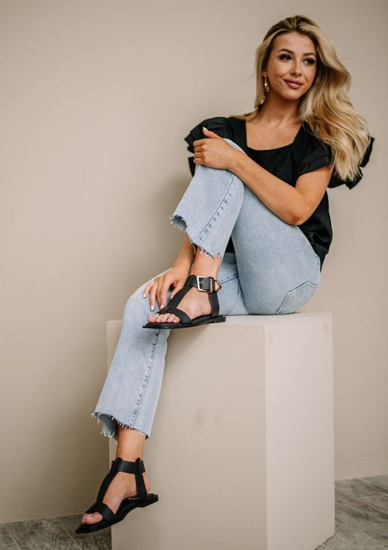 Women's casual sandals with buckle strap in black by Maker's Shoes worn with light blue jeans and black top