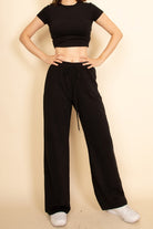 Woman wearing a casual wide-leg pants outfit in black with a cropped top and white sneakers
