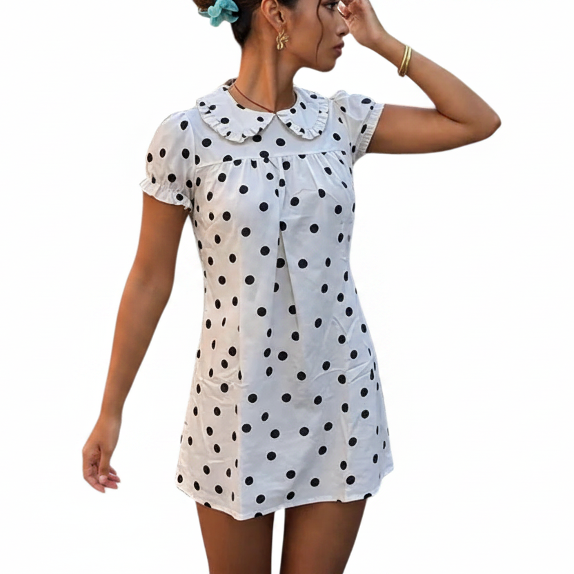 Woman wearing a white polka dot dress holding a yellow drink and a straw on a white background