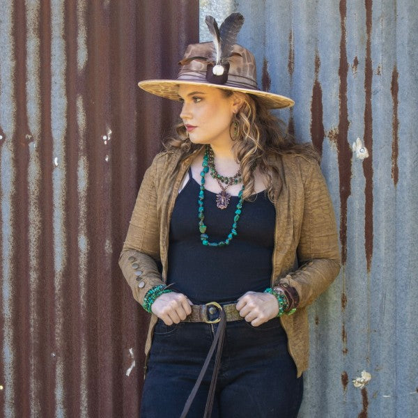 Woman wearing a chunky turquoise bracelet with a stylish outfit and a wide-brimmed hat