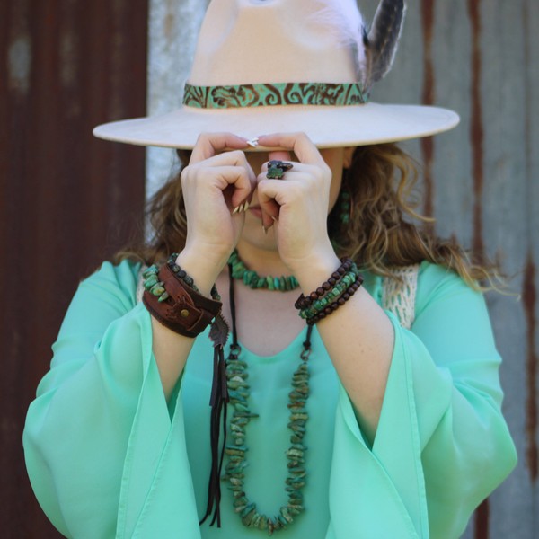 Woman wearing a chunky turquoise bracelet with matching accessories and a stylish hat