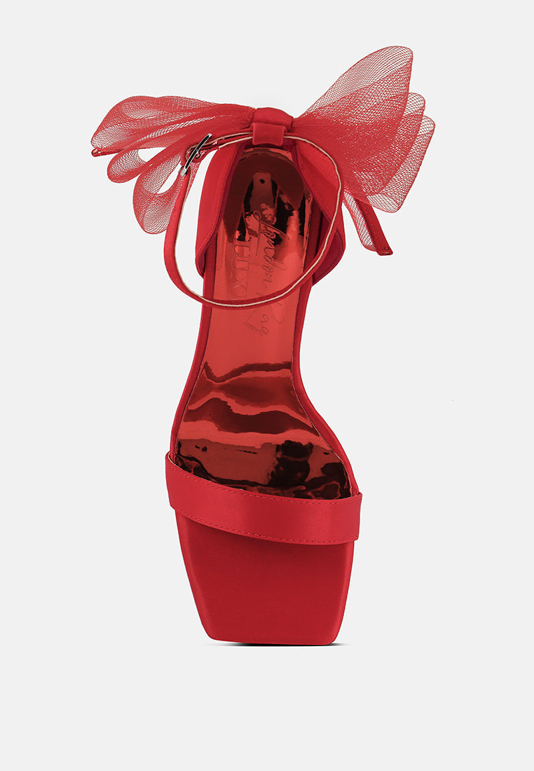 Stylish red clear high heeled sandals with a large bow and ankle strap for elegant occasions