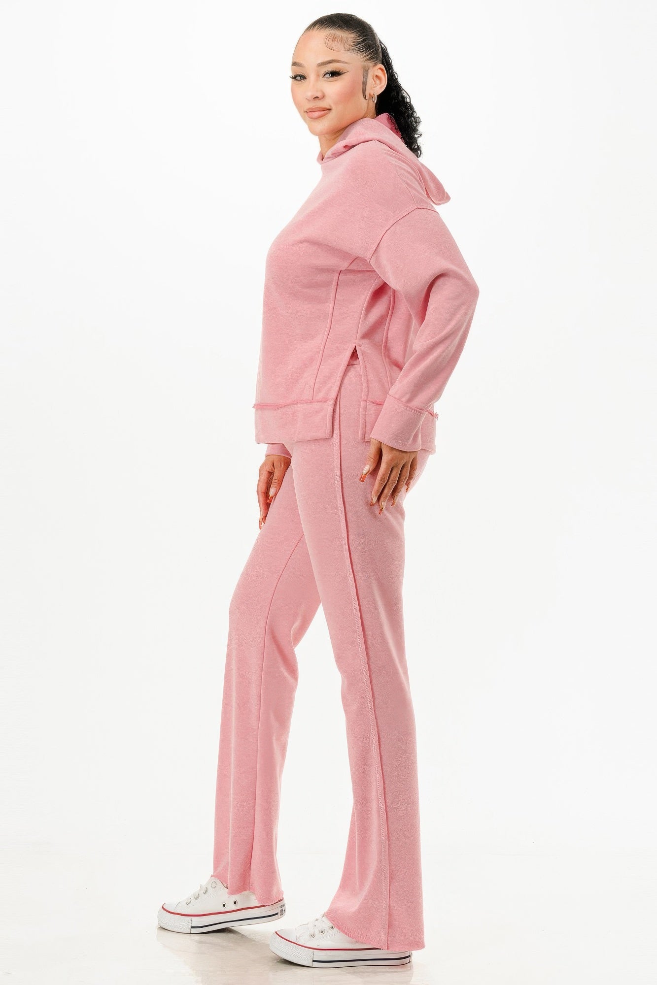 Woman wearing comfortable pink hoodie and pants set by VacationGrabs with white sneakers